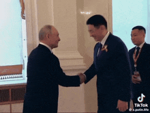 a man in a suit and tie shakes hands with another man