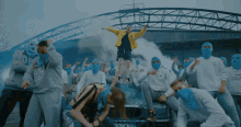 a man in a yellow jacket is surrounded by people in blue masks