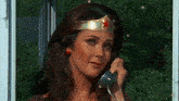 a woman dressed as wonder woman is talking on a telephone .