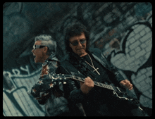 two men standing next to each other with one wearing a guitar strap that says ozzy on it