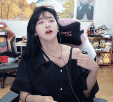 a woman wearing headphones sits in a chair with a secret lab pillow on it