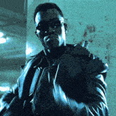 a man wearing sunglasses and a leather jacket is standing in front of a wall with blood on it