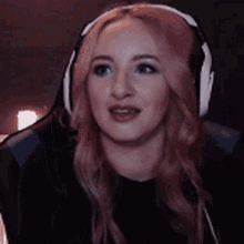 a woman with pink hair is wearing headphones while sitting in a gaming chair .