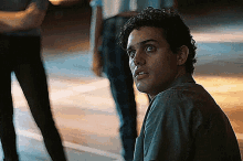 a man with curly hair is sitting on the ground and looking at something .