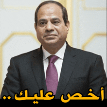 a man in a suit and tie with arabic writing on the bottom right