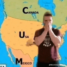 a man is standing in front of a map of the united states covering his face .