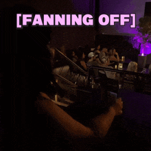 a woman taking a picture of a group of people in a dark room with the words [ fanning off ] above her