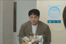 a man in a suit is holding a bouquet of flowers in front of him