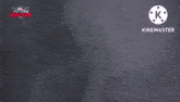 a close up of a person holding a gun in a dark room with a k logo in the corner .