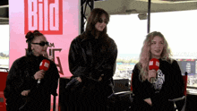 a group of women standing in front of a sign that says bild