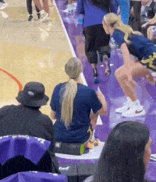 a woman sits on a foam roller on a purple court