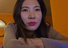 a close up of a woman 's face wearing a grey sweater