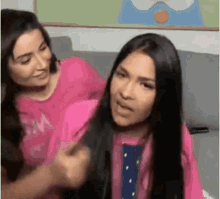 two women are sitting next to each other on a couch .