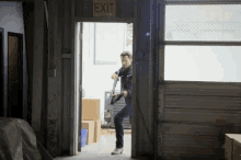 a man is walking through an exit sign