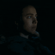 a woman is sitting in a dark room looking at a screen .