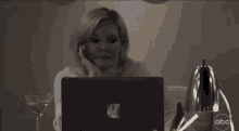 a woman sitting in front of a laptop with the abc logo on the bottom