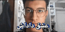 a young man wearing glasses and ear buds is looking at the camera with a foreign language on his face .