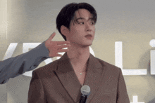 a man in a brown suit is being touched by another man