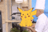 a man in a chef 's hat is holding a pikachu in his hands
