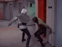 a couple of men are fighting in a hallway .