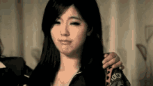 a woman with long black hair is holding a person 's arm and making a funny face .