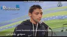 a man is speaking into a microphone with the website www.facebook.com/redouagee31hd visible