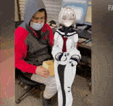a man wearing a face mask sits next to a cartoon character with the word fa on the bottom right