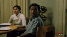 a man and a woman are sitting at a table with plates on it and a sign that says ' full ' in red