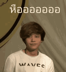 a young man wearing a white t-shirt with waves written on it .