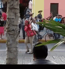 a woman in a red purse is walking down a street with other people