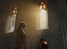 a man in a suit stands in front of a stained glass window with the word kepler below him