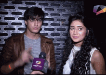 a man and a woman are standing next to each other with a purple microphone that says ' india forums ' on it