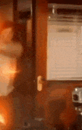 a blurred image of a room with a fire coming out of a door