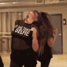 a woman wearing a shirt that says " let me take a selfie "