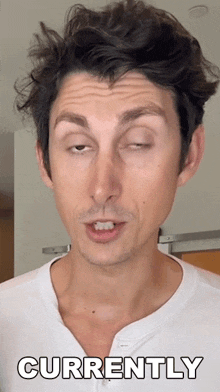 a man in a white shirt is making a funny face and the word currently is on the bottom right