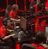 a man wearing headphones is sitting in front of a computer with a red light behind him that says triumph
