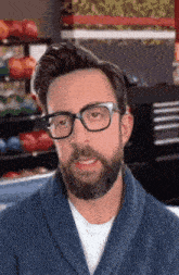 a man with a beard and glasses is wearing a blue sweater and making a funny face .