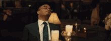 a man in a suit and tie is sitting in a room with candles .
