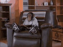 a chimpanzee is sitting in a chair with his feet crossed and a blanket on the back
