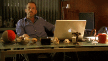 a man sitting at a desk with an apple laptop
