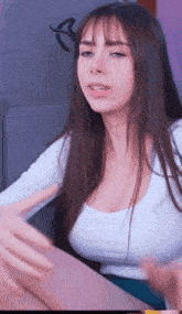 a woman with long brown hair and a white shirt is sitting on a chair .