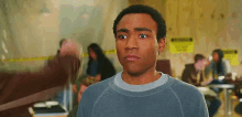 a man in a blue sweater is making a funny face while standing in a room .