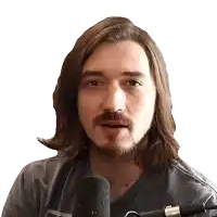 a man with long hair and a beard is standing in front of a microphone