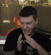 a man wearing a black shirt with a skull on it is talking into a microphone