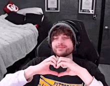 a man in a pittsburgh shirt is making a heart with his hands