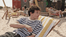 a man in a striped shirt sits on a beach chair