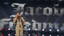a man stands on a stage in front of a sign that says aew