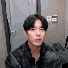 a young man wearing a denim jacket is looking at the camera