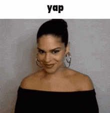 a woman wearing hoop earrings and a bun is smiling and looking at the camera .