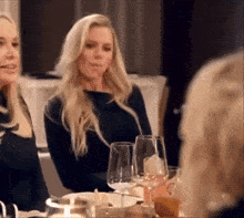 a woman is sitting at a table with glasses of wine